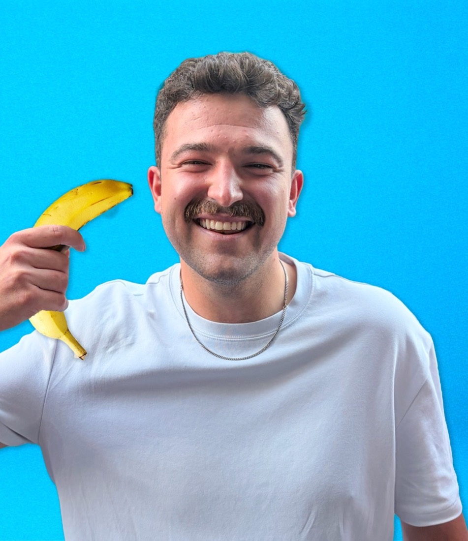 Jonny holding a banana against a blue background.